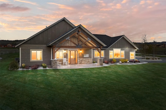 back house at dusk with a patio and a yard