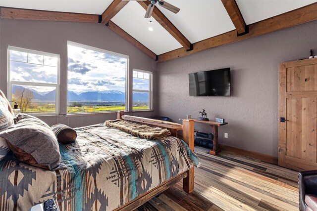 bedroom featuring a mountain view, lofted ceiling with beams, hardwood / wood-style floors, and ceiling fan