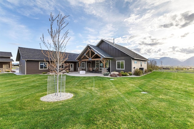 rear view of house featuring a mountain view, a patio area, and a lawn