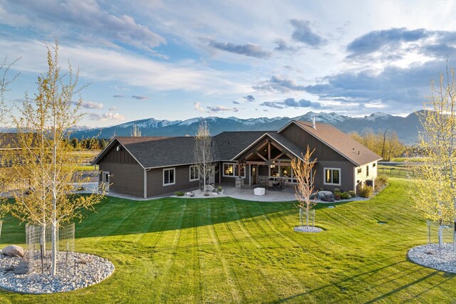 back of property with a mountain view, a patio area, and a lawn