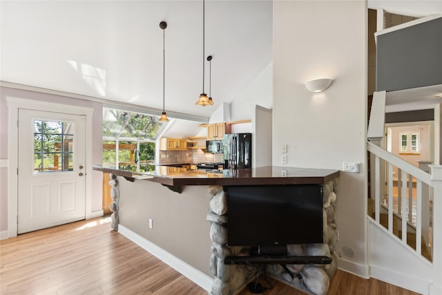 963 Colorado Ave, Whitefish, MT 59937 - kitchen featuring black appliances, light wood-style flooring, a peninsula, a breakfast bar, and dark countertops