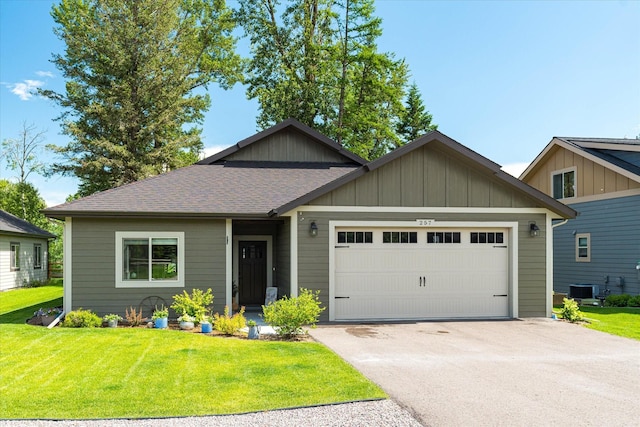 view of front of house with cooling unit, a garage, and a front lawn