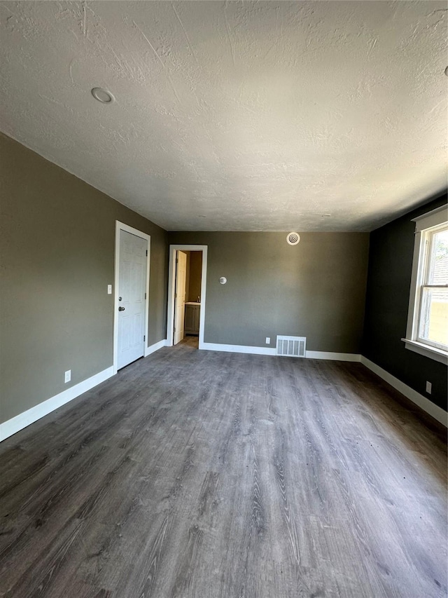 unfurnished room featuring dark hardwood / wood-style flooring and a textured ceiling