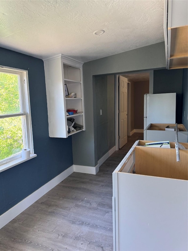 kitchen with white refrigerator, wood-type flooring, and a textured ceiling