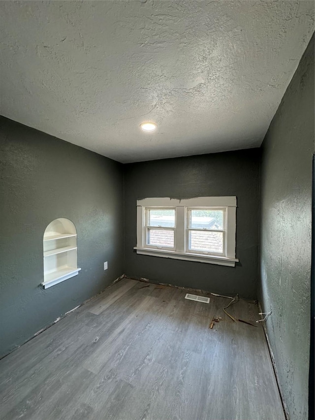 empty room featuring built in shelves and a textured ceiling