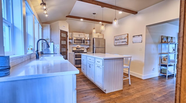 kitchen featuring stainless steel appliances, beam ceiling, a center island, white cabinetry, and hanging light fixtures