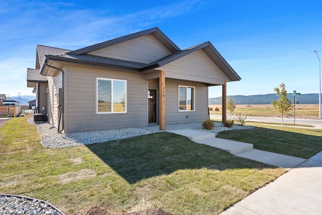 view of front facade with a mountain view, a front lawn, and central AC