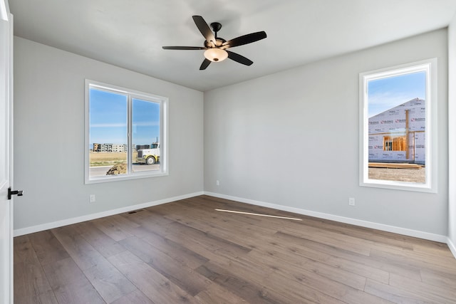 unfurnished room with light wood-type flooring, ceiling fan, and a wealth of natural light