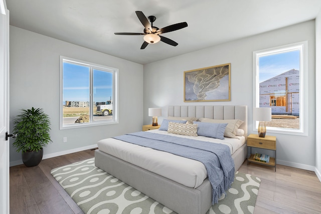 bedroom with multiple windows, wood-type flooring, and ceiling fan