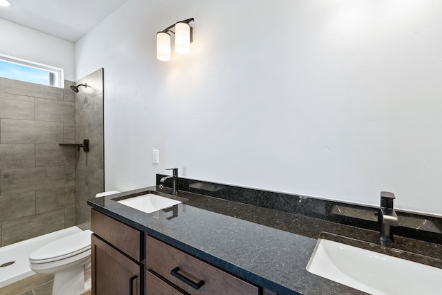 bathroom with a tile shower, vanity, and toilet