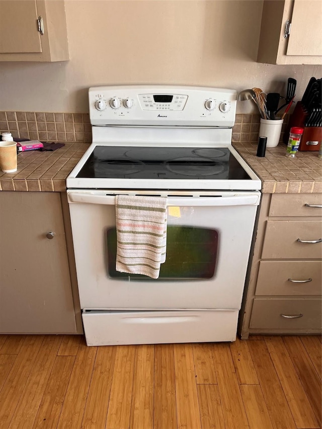 kitchen with white electric range oven, tile countertops, and light hardwood / wood-style flooring