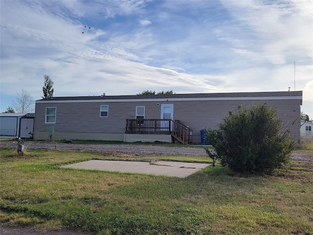 back of house with a wooden deck, a shed, and a lawn