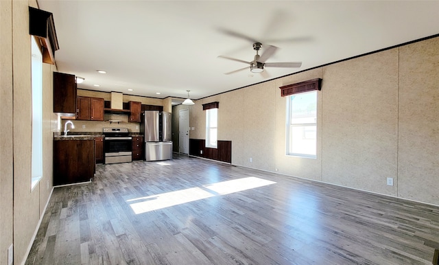 unfurnished living room featuring sink, light hardwood / wood-style flooring, and ceiling fan