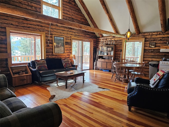 living room with beamed ceiling, a wealth of natural light, rustic walls, high vaulted ceiling, and wood-type flooring