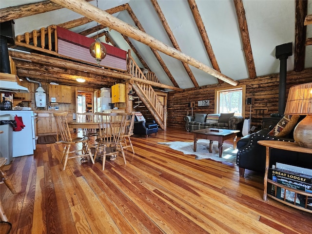 dining space with beam ceiling, a wood stove, log walls, wood-type flooring, and high vaulted ceiling