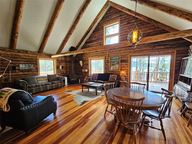 living room featuring a wood stove, high vaulted ceiling, hardwood / wood-style floors, beamed ceiling, and a wealth of natural light