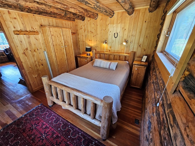 bedroom with dark wood-type flooring, wooden walls, and beam ceiling