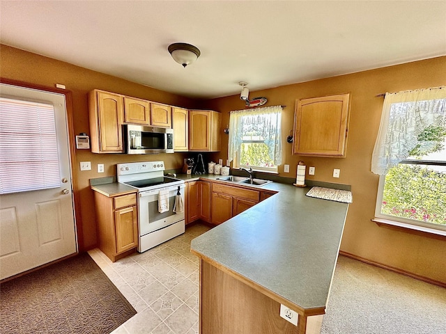 kitchen featuring electric stove, stainless steel microwave, light brown cabinets, a sink, and a peninsula