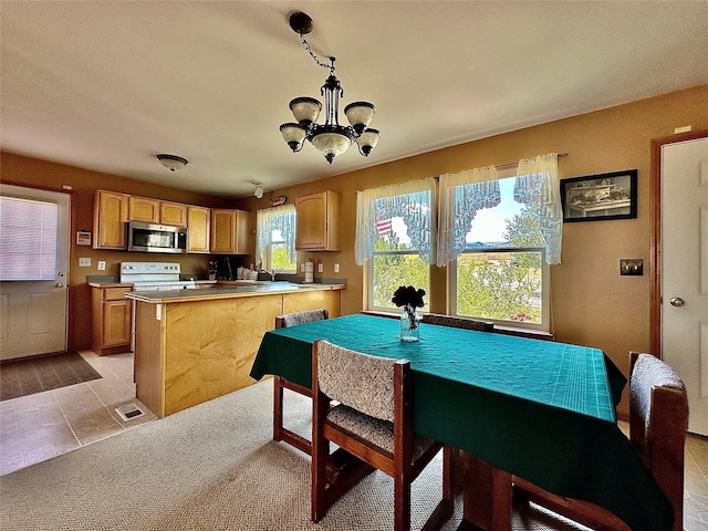 interior space with white electric range, light countertops, stainless steel microwave, decorative light fixtures, and an inviting chandelier