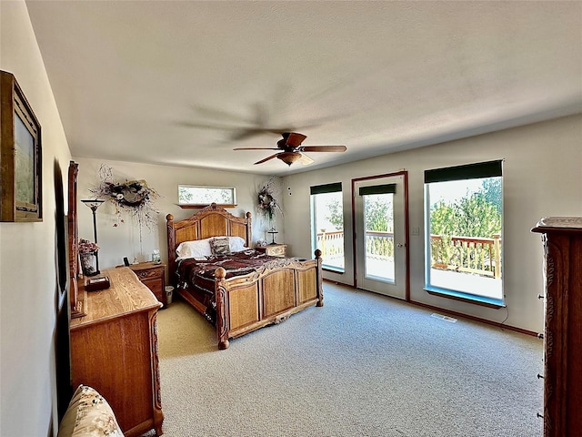 bedroom with access to exterior, light colored carpet, visible vents, and a ceiling fan