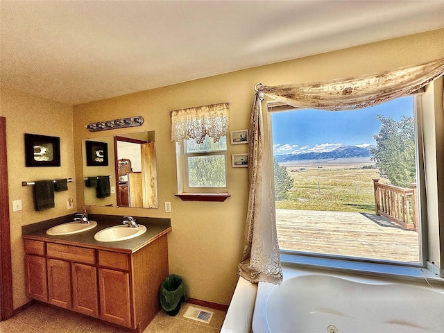 full bathroom featuring double vanity, visible vents, a mountain view, and a sink