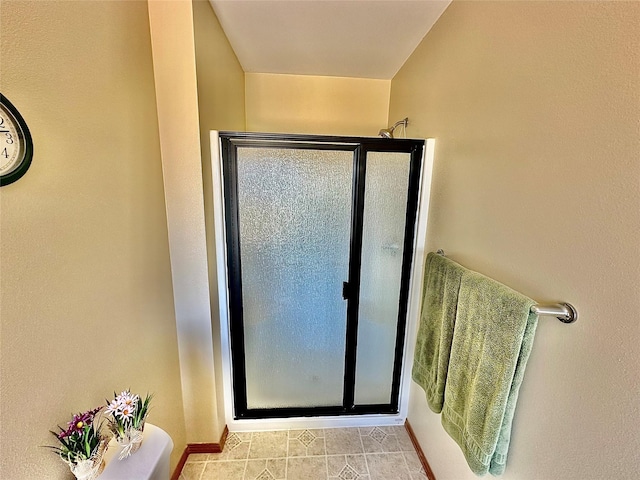 full bathroom featuring a shower stall and baseboards