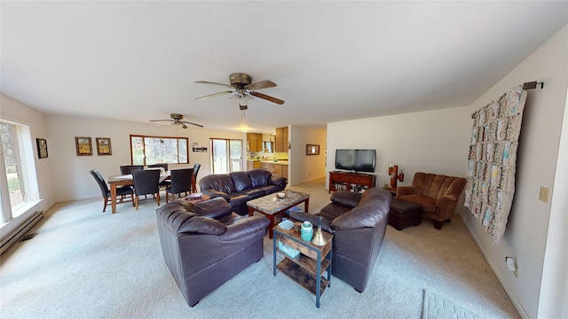living area featuring baseboard heating, light colored carpet, baseboards, and a ceiling fan