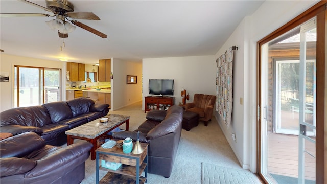 living area featuring light carpet, a wealth of natural light, baseboards, and ceiling fan