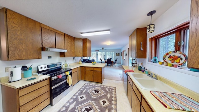 kitchen with light countertops, double oven range, a peninsula, and under cabinet range hood