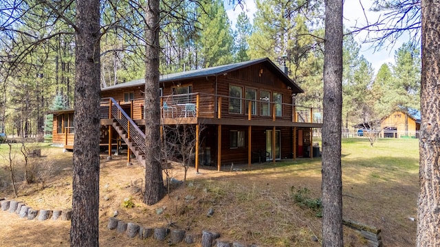 rear view of property featuring a yard, a deck, and stairs