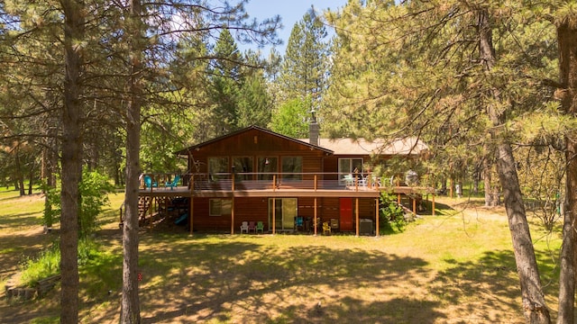 back of property featuring stairs, a wooden deck, and a lawn