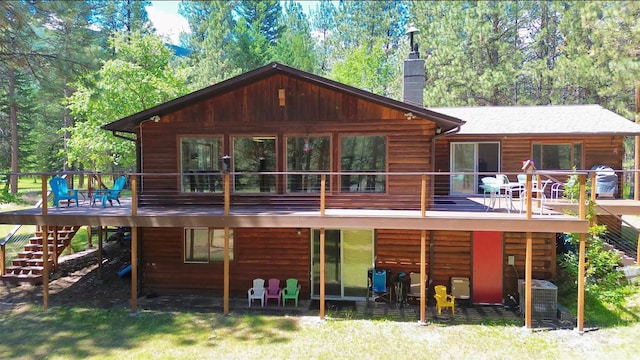 rear view of property featuring a chimney, log veneer siding, stairs, central AC, and a wooden deck