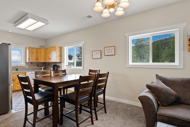 carpeted dining room featuring an inviting chandelier