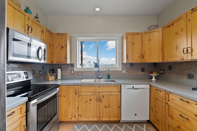 kitchen featuring light brown cabinetry, appliances with stainless steel finishes, backsplash, and sink