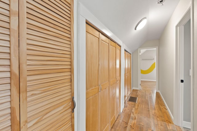 hall with light hardwood / wood-style floors and lofted ceiling