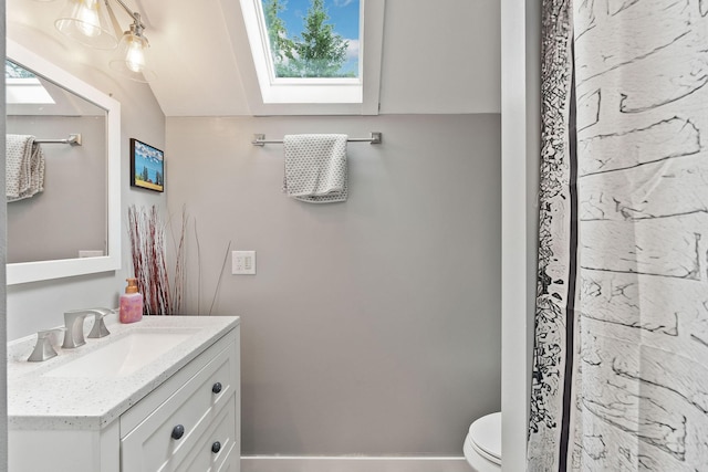 bathroom featuring toilet, vaulted ceiling with skylight, and vanity