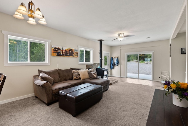 carpeted living room with ceiling fan with notable chandelier and a wood stove