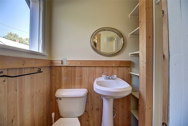 bathroom featuring wooden walls and toilet