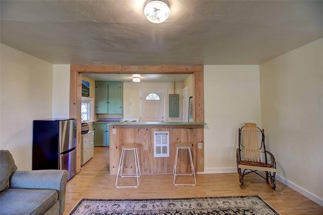 kitchen featuring stainless steel refrigerator, kitchen peninsula, light hardwood / wood-style flooring, electric panel, and green cabinets