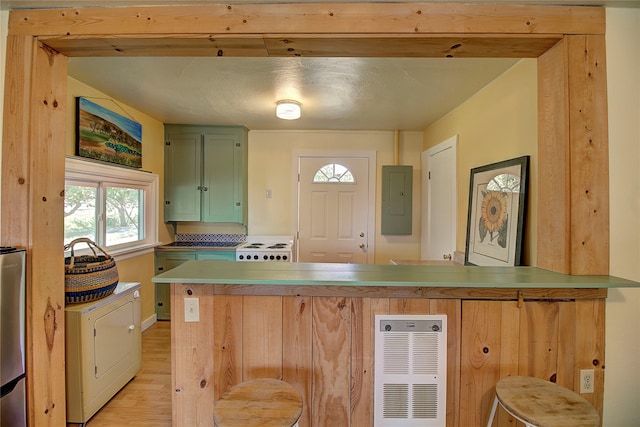 kitchen with electric panel, kitchen peninsula, green cabinetry, a kitchen breakfast bar, and light hardwood / wood-style floors