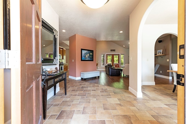 entrance foyer featuring lofted ceiling, light wood-type flooring, and a textured ceiling