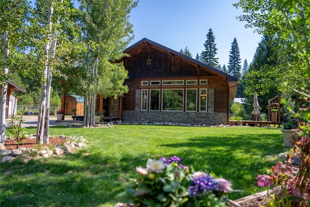 rear view of property with a yard and a storage unit