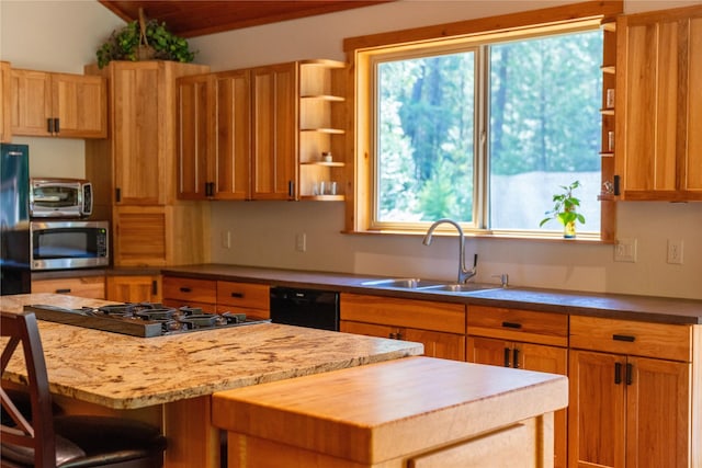 kitchen featuring sink, wooden counters, a kitchen breakfast bar, a center island, and black appliances