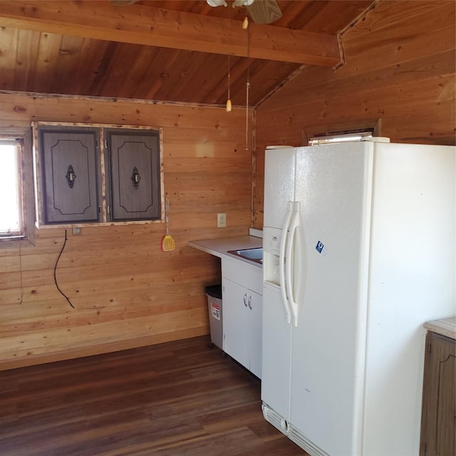 kitchen with vaulted ceiling with beams, white refrigerator with ice dispenser, wooden walls, and wooden ceiling