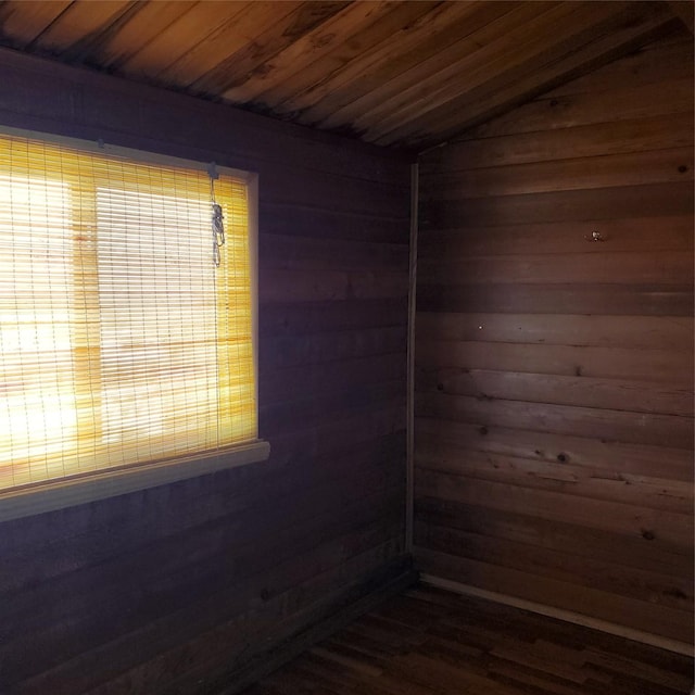empty room featuring wood ceiling and wooden walls