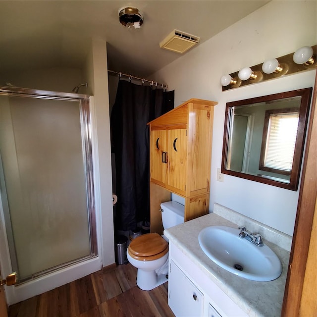 bathroom featuring a shower stall, toilet, vanity, and wood finished floors