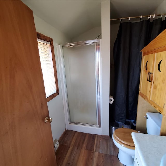 bathroom featuring lofted ceiling, toilet, wood finished floors, and a stall shower
