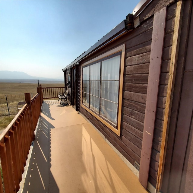 view of side of home featuring fence, a mountain view, and log veneer siding