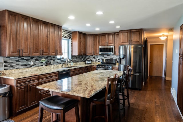 kitchen with a sink, appliances with stainless steel finishes, a kitchen breakfast bar, and decorative backsplash