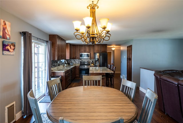 dining space featuring baseboards, a notable chandelier, dark wood finished floors, and visible vents